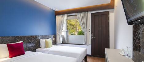 A hotel room with two beds, a TV, a desk, and a window with curtains.