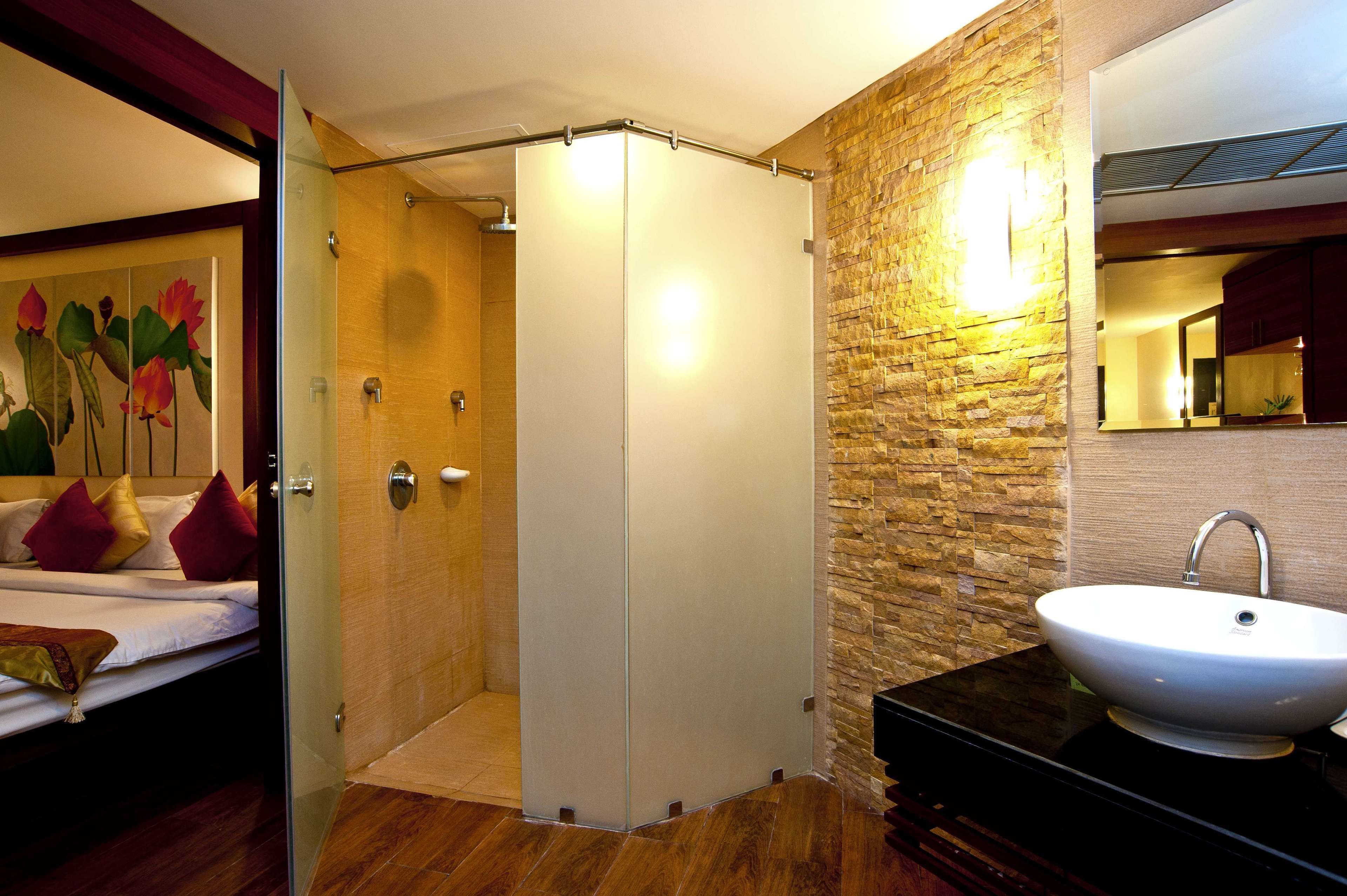 A modern bathroom with a glass shower enclosure, a stone wall, and a white sink.