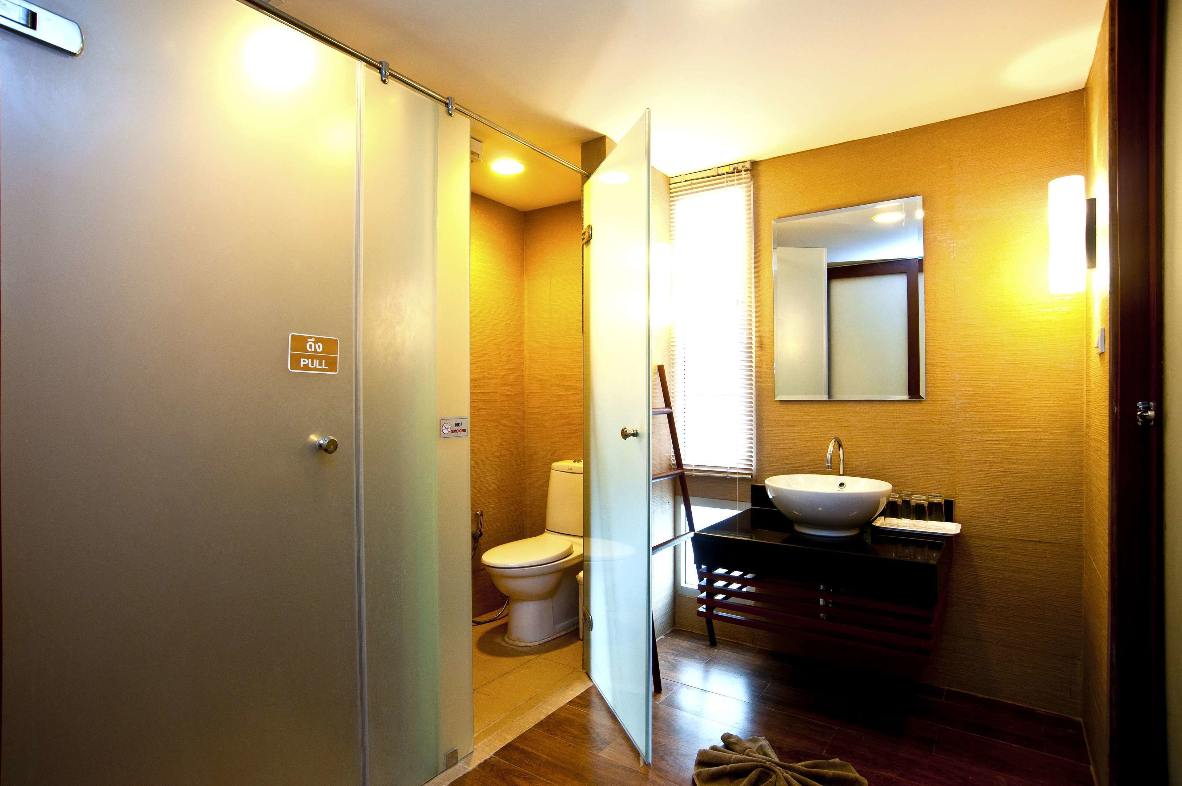 Un baño pequeño con inodoro, lavamanos y espejo sobre el lavamanos.