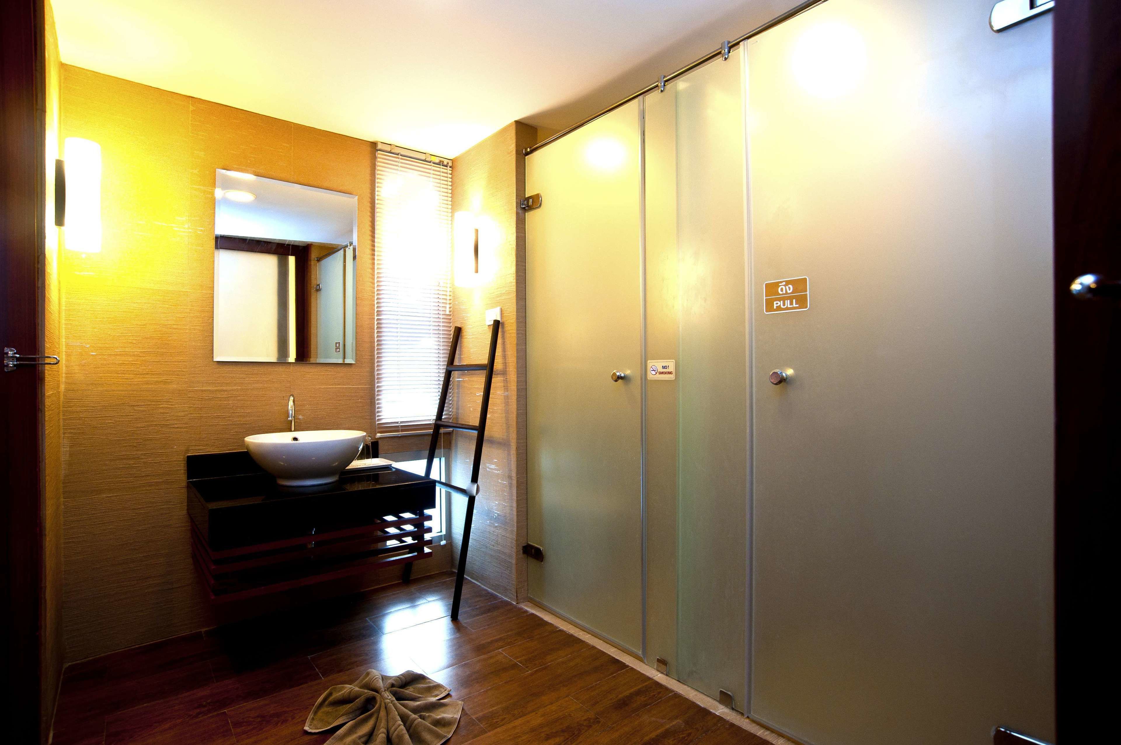 A bathroom with a sink, mirror, and a towel on the floor.