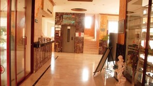 A hotel lobby with a marble floor, a reception desk, a staircase, and a statue. - Sailor Apart Hotel (Alanya)