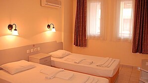 A hotel room with two beds, a nightstand, an air conditioning unit, and two wall-mounted lamps. - Sailor Apart Hotel (Alanya)