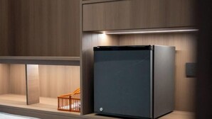 Une cuisine moderne dotée d’un réfrigérateur encastré, de meubles de rangement en bois et d’un petit tabouret en bois.