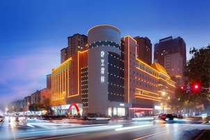 Un hotel de varios pisos con un diseño moderno, que presenta una estructura cilíndrica destacada y una serie de balcones.