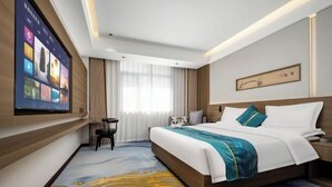 Une chambre d’hôtel avec un grand lit, un téléviseur fixé au mur, un bureau et une chaise.