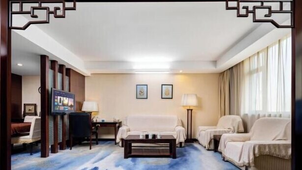 Une chambre d’hôtel avec un grand lit, un canapé, une table basse et un téléviseur.