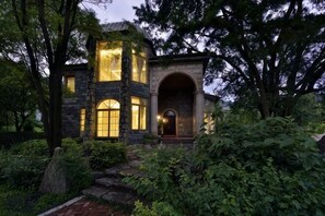 A stone house with a large arched entrance, a second-story balcony, and a well-lit front door. - Guilin Landscape Golf Resort (Guilin)