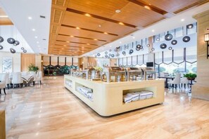 En modern hotellobby med en central receptionsdisk, en sittgrupp och ett stort fönster som släpper in naturligt ljus.