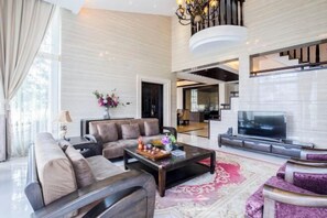 A modern living room with a sofa, coffee table, and TV. There is a staircase leading to another level. - Guilin Landscape Golf Resort (Guilin)