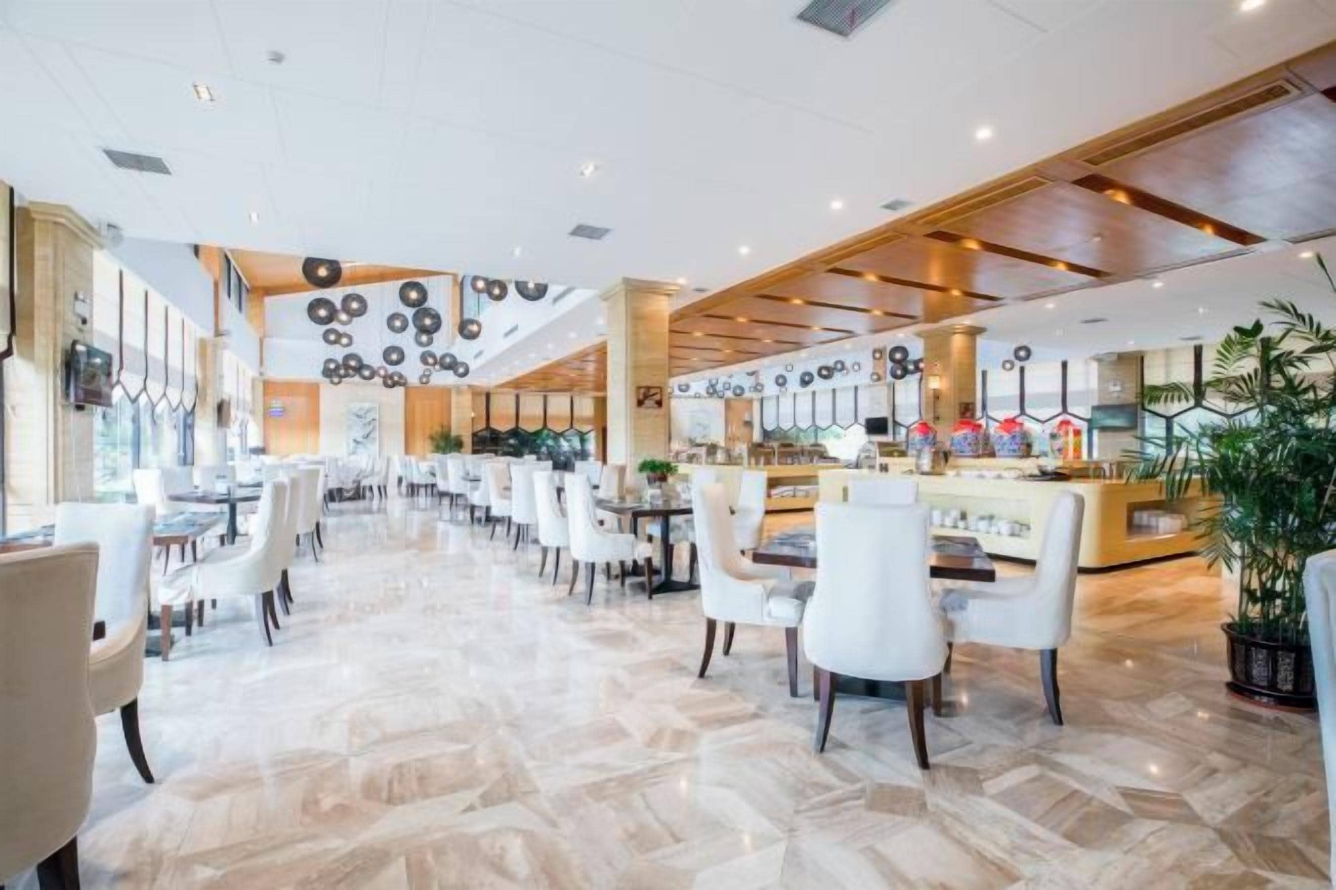 Een ruime hotel lobby met een bar in het midden, diverse zithoeken en een gepolijste marmeren vloer.