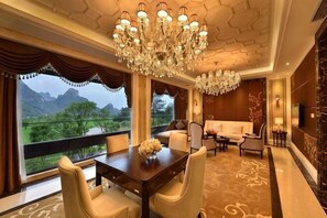 A room with a dining table, chairs, a chandelier, a sofa, and a view of greenery. - Guilin Landscape Golf Resort (Guilin)