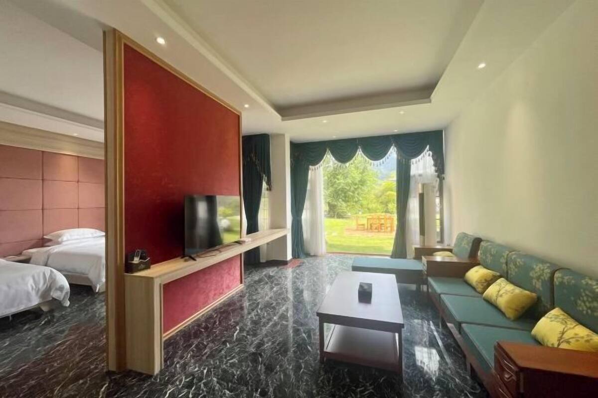 A hotel room with a bed, a TV on a stand, a sofa, and a table.