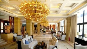 Un hall d’entrée spacieux, agrémenté d’un magnifique lustre, de coins salons confortables et d’un comptoir d’accueil.