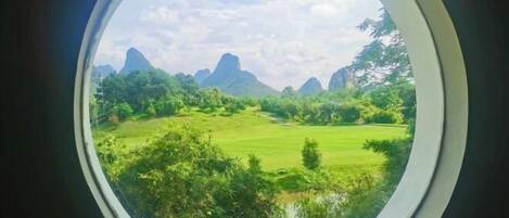 Vista circular desde una ventana que muestra un paisaje con montañas y vegetación.