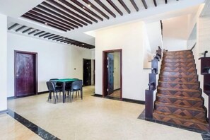 A spacious interior with a dining area, a staircase with a geometric pattern, and a modern ceiling design. - Guilin Landscape Golf Resort (Guilin)