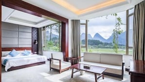 Une chambre d’hôtel comprenant un lit, un canapé et une table basse, de grandes fenêtres offrant une vue sur les montagnes et un plafond en bois.
