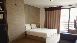 A modern hotel room with a bed, a sofa, a wardrobe, and a view of the outside. - Mooks Residence (Pattaya)