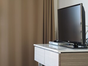 A modern flat-screen TV on a white and wooden TV stand with a remote control and a DVD player. - Mooks Residence (Pattaya)