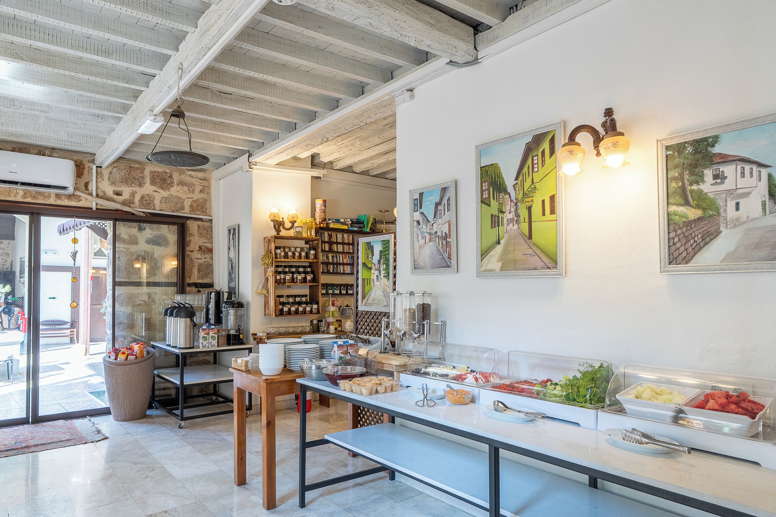 A breakfast buffet area with a variety of food options, a coffee station, and a seating area with a bench.