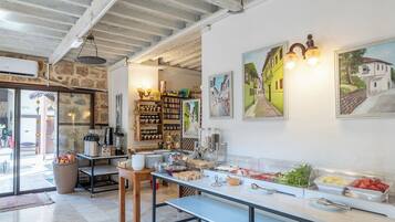 A breakfast buffet area with a variety of food options, a coffee station, and a seating area with a bench.