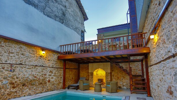 A stone-walled pool area with a wooden deck and lounge chairs. - Atelya Art Hotel (Antalya)