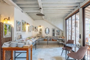 A dining area with a buffet setup, a table with stacked plates, and a seating area with chairs.