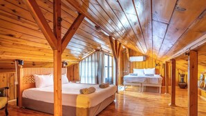 A wooden cabin with a large bed and a smaller bed in a cozy room with wooden floors and beams. - Atelya Art Hotel (Antalya)