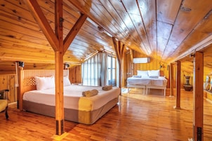 A wooden cabin with a large bed and a smaller bed in a cozy room with wooden floors and beams.