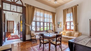 A room with a wooden dining table, chairs, a sofa, and a large window with curtains. - Atelya Art Hotel (Antalya)