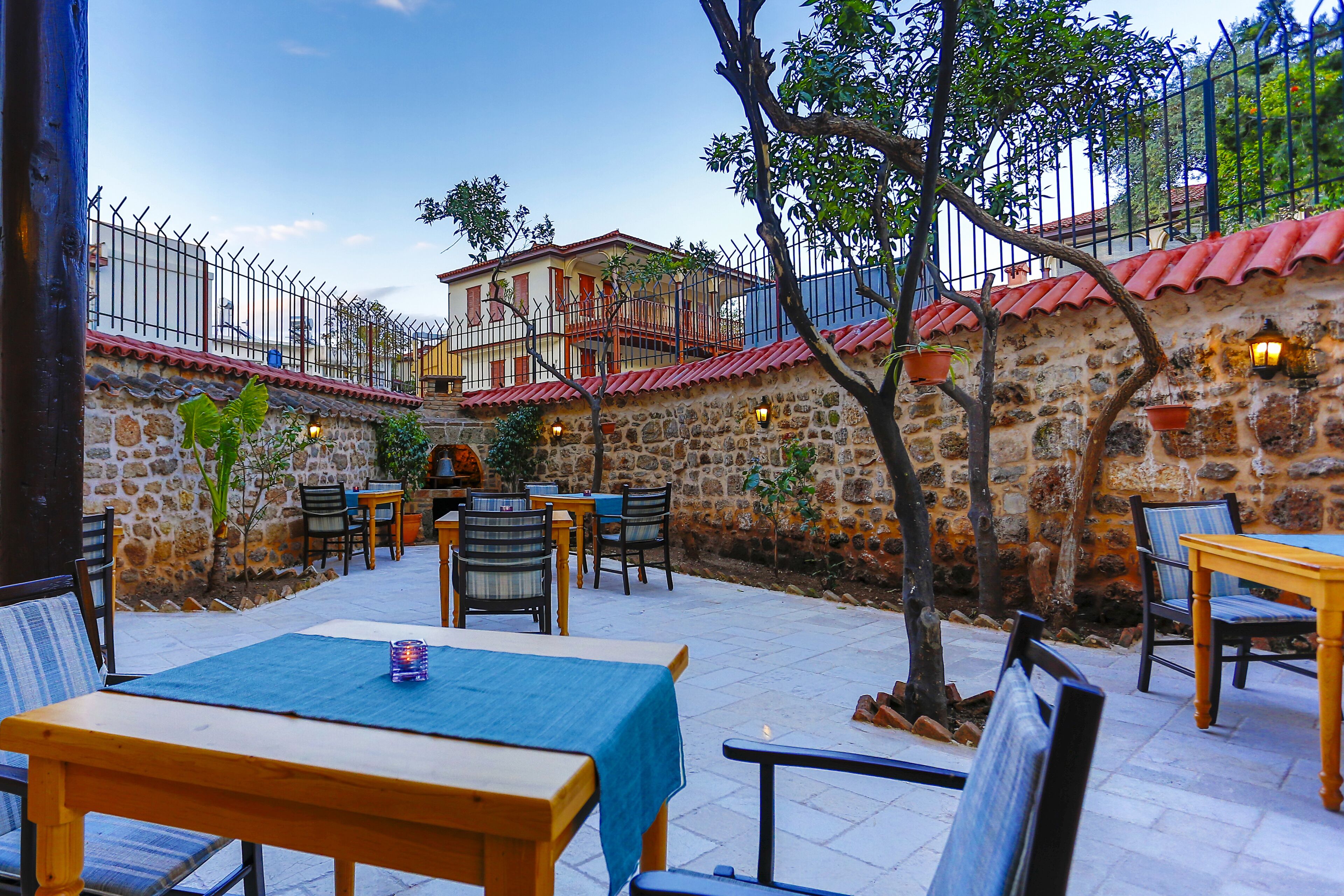 An outdoor patio with stone walls, a fenced area, and tables with chairs.