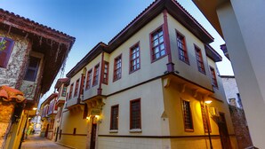 A narrow street with buildings featuring traditional architecture, including a corner building with a visible entrance and a sign above it. - Atelya Art Hotel (Antalya)