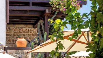 A two-story building with a balcony, stone wall, and a hanging flower basket.