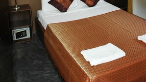A hotel room with a bed, a nightstand, an air conditioner, a painting, and a window with curtains. - Green Canyon Resort (Koh Samui)