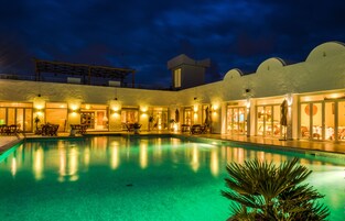 Una piscina al aire libre, sombrillas, sillones reclinables de piscina
