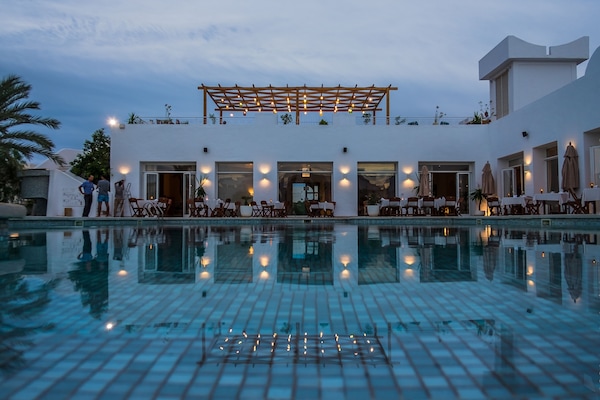 Una piscina al aire libre, sombrillas, tumbonas