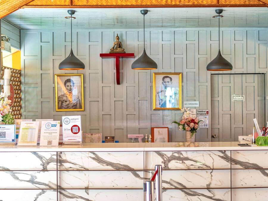 Zona de recepción con mostrador de mármol, fotografías enmarcadas, una estatua de Buda y un cartel de 'No Fumar'.