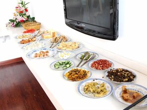 A dining table with various dishes and a television in the background. - GreenTree Inn Nantong Tongzhou District Government  East Bihua Road Business Hotel (Nantong)