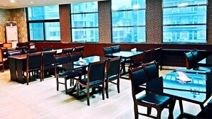 A conference room with multiple tables and chairs, large windows with a city view, and a whiteboard on the left. - GreenTree Inn Nantong Tongzhou District Government  East Bihua Road Business Hotel (Nantong)