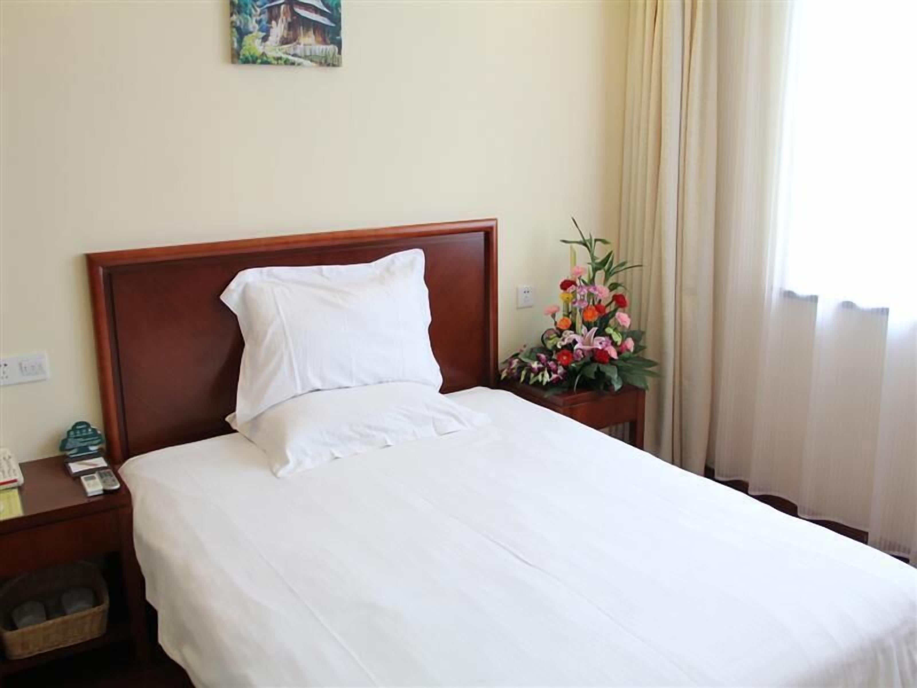 A neatly made bed with white linens in a hotel room.