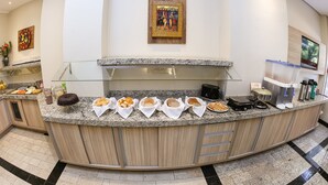 A breakfast bar with bread, pastries, and a coffee machine.