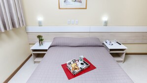 A hotel room with a bed, bedside tables, a framed picture on the wall, and a breakfast tray on the bed.