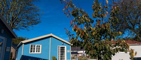 A blue single-story house with a front porch, a small garden, and a clear blue sky.