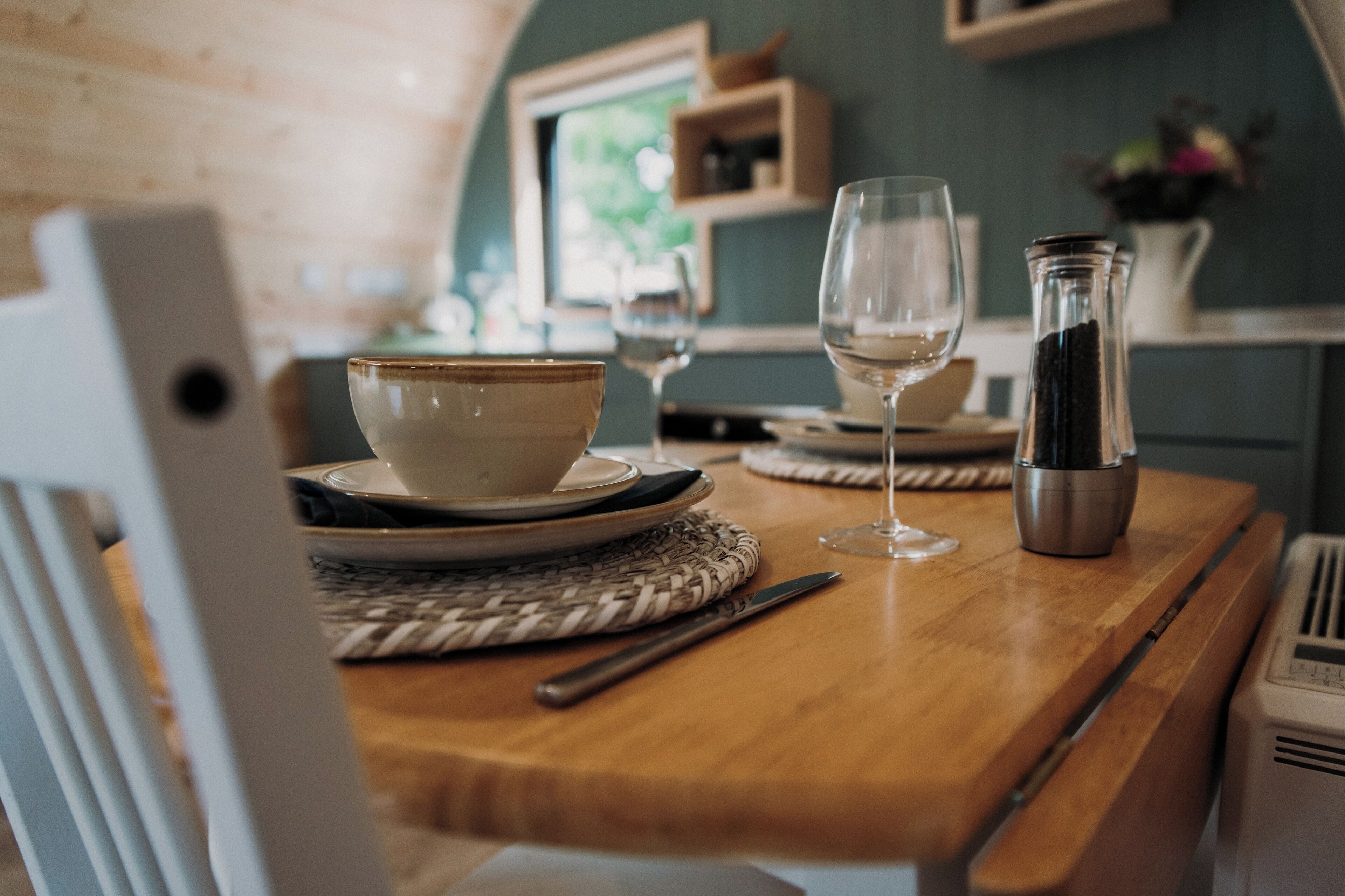 Una mesa de madera con un cuenco, una copa de vino y una botella.