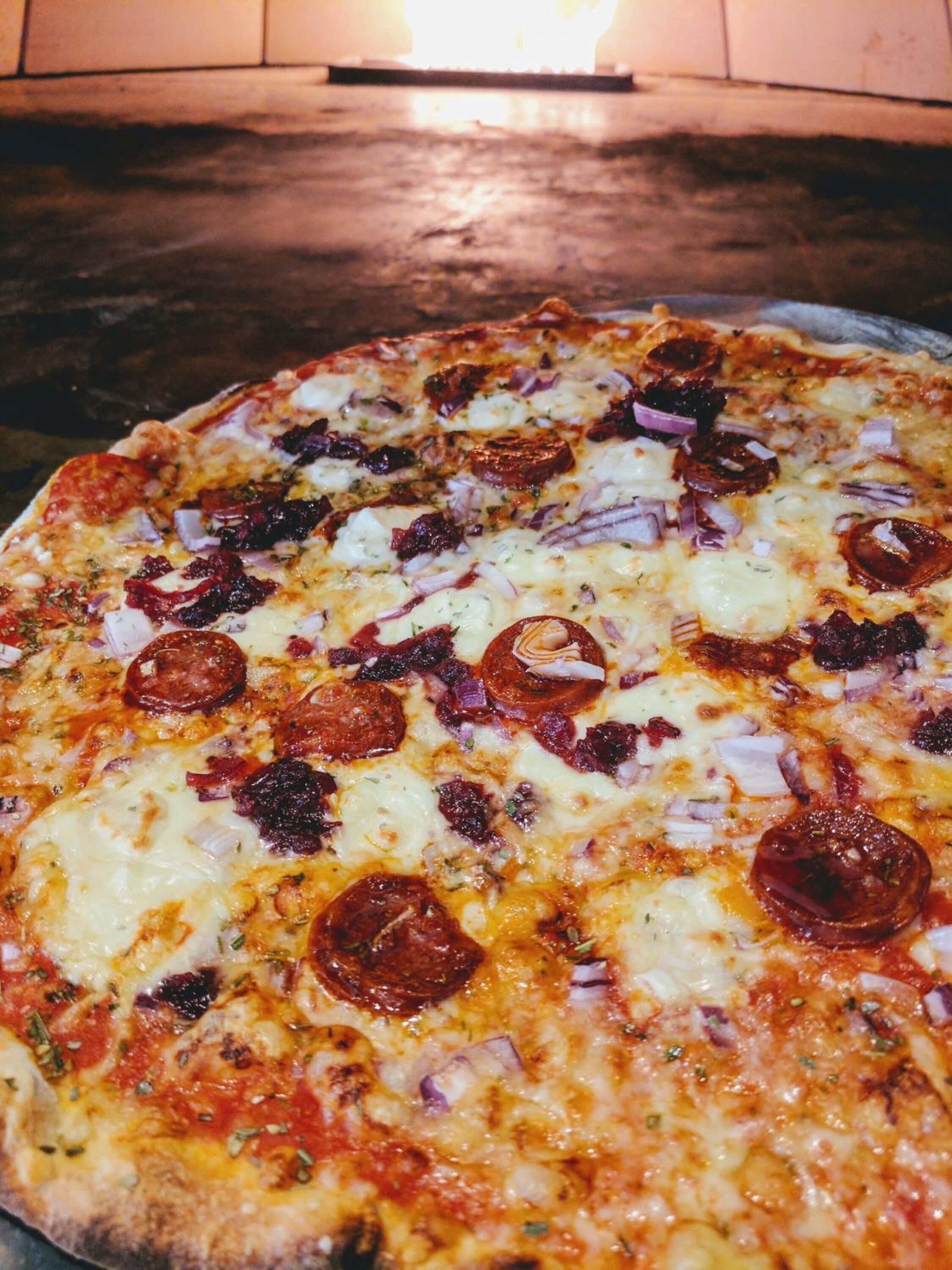 Une pizza à la saucisse piquante et aux oignons, cuite au four.