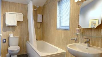 Een moderne badkamer met een bad, toilet en wastafel.