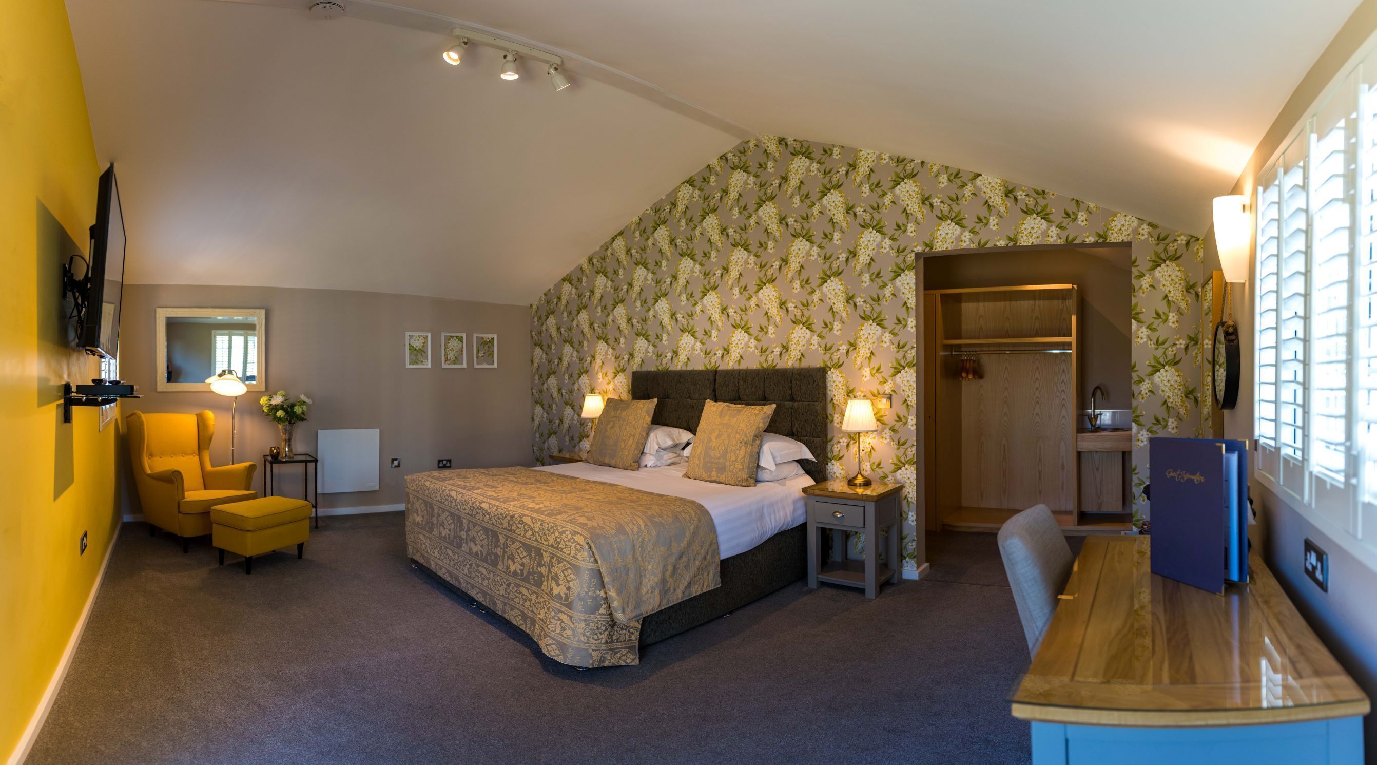 A bedroom with a bed, bedside tables, a chair, a desk, and a wardrobe.