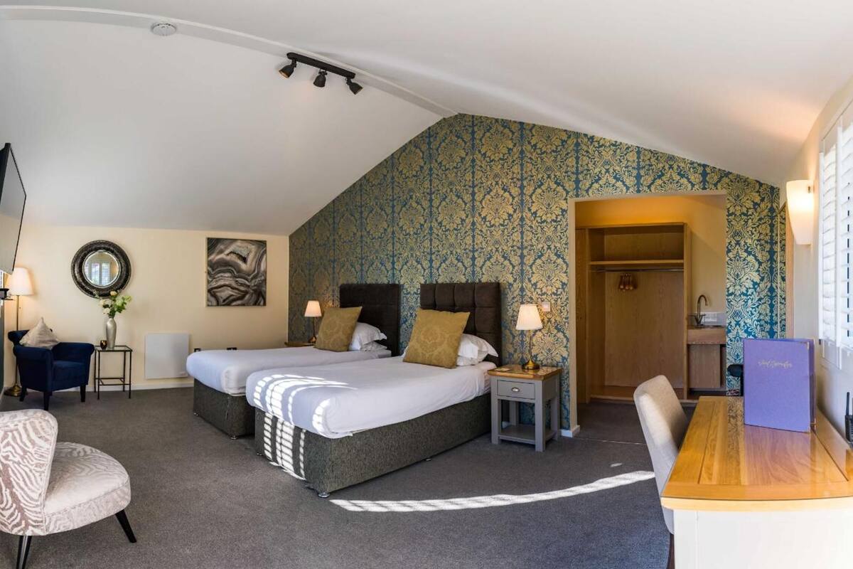 A bedroom with two beds, a desk, a chair, a mirror, and a wardrobe.