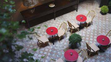 Una terraza con suelo estampado, sillas de mimbre y mesas de color rojo.