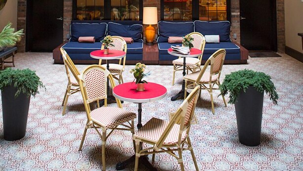 A courtyard with a seating area, tables, and potted plants. - The Broome (New York)