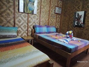 A room with two wooden beds, a woven wall, and a painting of flowers.